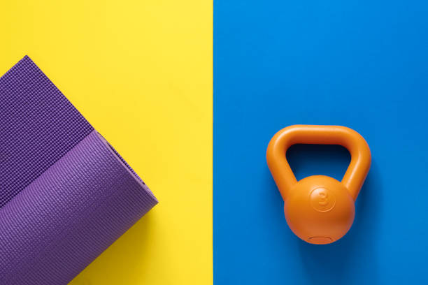 zeit für die ausübung von sport-ausrüstung-konzept mit yoga-matte und kettlebell auf tabelle hintergrundfarbe - gym yellow muscular build dumbbell stock-fotos und bilder