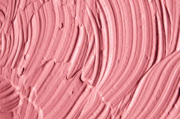 Pink cosmetic clay (facial mask, cream) texture close up, selective focus. Abstract background with brush strokes.