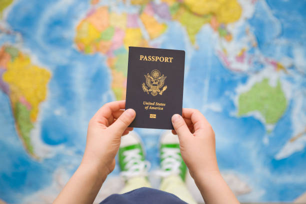 Child's hand holding US passport. Map background. Ready for traveling. Open world.