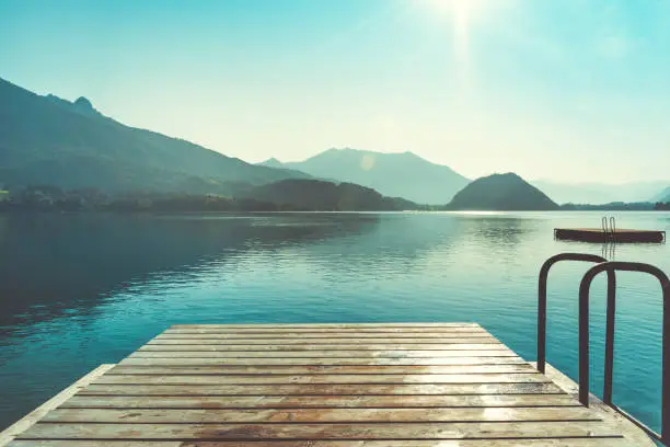 Wooden jetty for swimming in mountain lake in Austria. Swimming at early morning. European resort in mountains