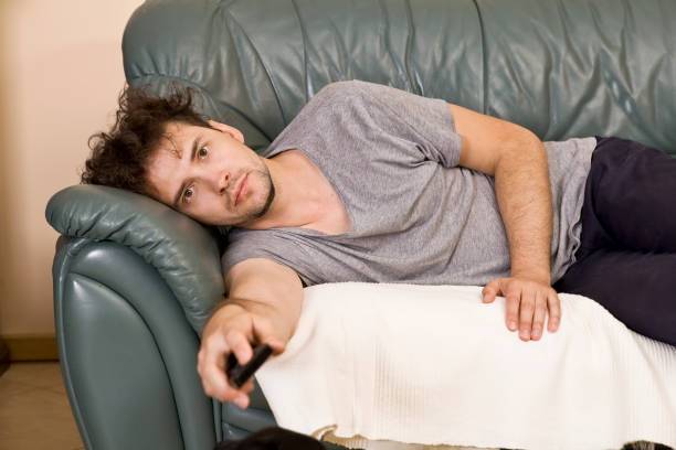 istock Lazy man with the remote on the couch 1038144352
