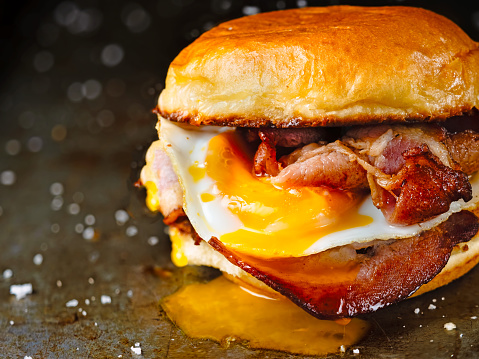 close up of rustic bacon egg breakfast sandwich bun