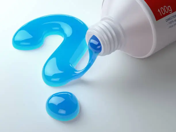 Photo of Toothpaste in the shape of question mark coming out from toothpaste tube. Brushing teeth dental concept.