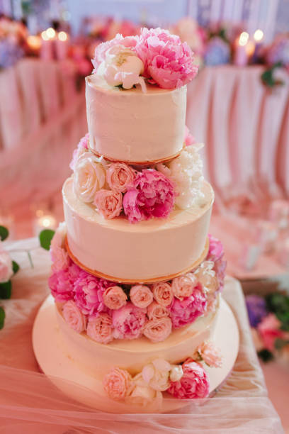 istock White wedding cake decorated with peony roses on pink restaurant background 1038188478