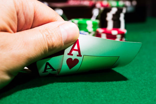 poker chips and ace of spades and ace of hearts on a green mat stock photo