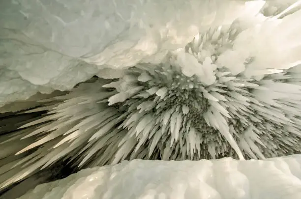 Photo of Backdrop of ice stalactites with a crack. White icicles in a frozen ice wall.