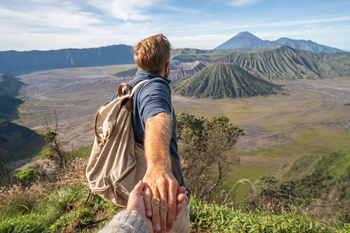 Follow me to concept, boyfriend leading person to volcanic landscape in Bromo, Indonesia.\nPeople travel concept