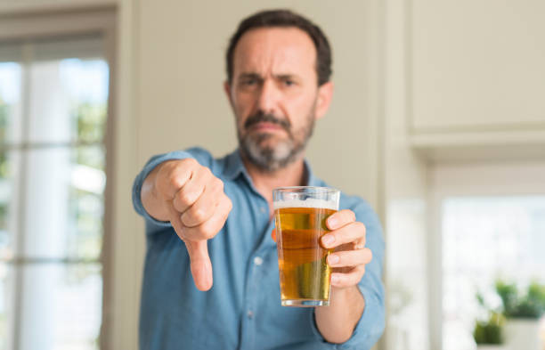 istock Middle age man drinking beer with angry face, negative sign showing dislike with thumbs down, rejection concept 1038253512