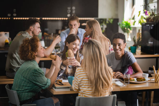 istock Large group of university students communicating while eating sandwiches on a lunch break at cafeteria. 1038314998