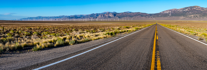 Empty desert road with wind turbines