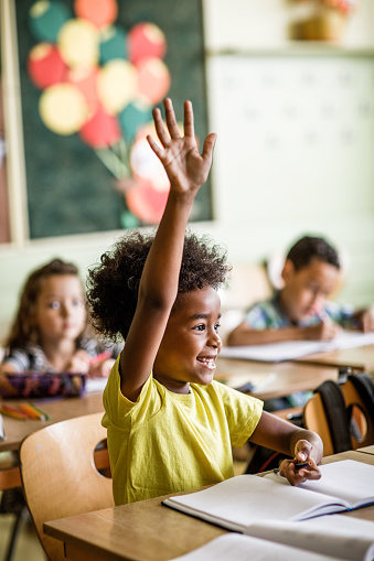 Americano africano estudiantes de primaria levantando su brazo para responder a la pregunta en una clase. photo