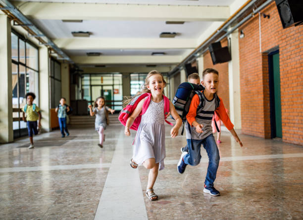 istock Happy school kids running down the hallway in elementary school. 1038330800