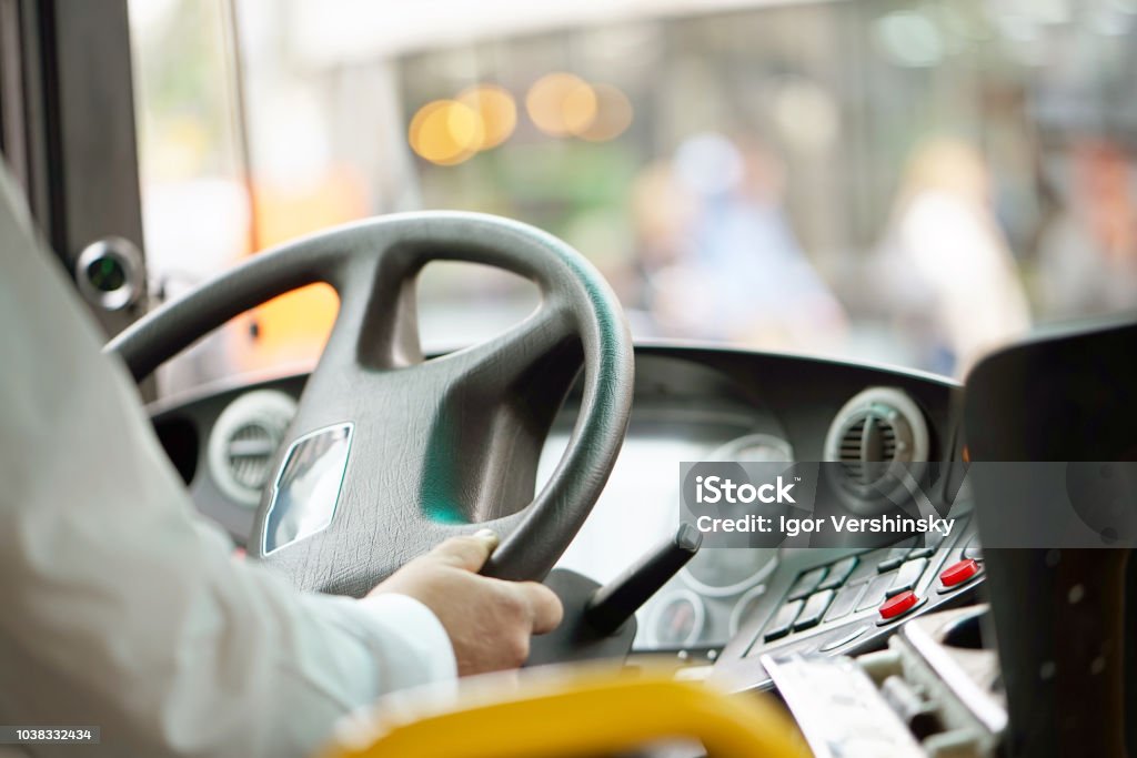 cropped shot of bus driver holding steering whee Hands of driver in a modern bus by driving.Concept - close-up of bus driver steering wheel and driving passenger bus Bus Stock Photo