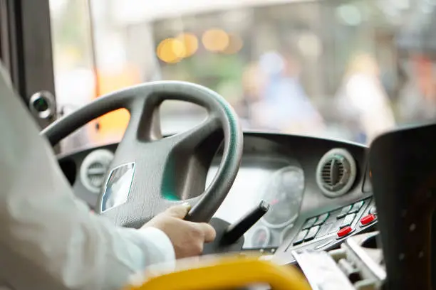 Hands of driver in a modern bus by driving.Concept - close-up of bus driver steering wheel and driving passenger bus