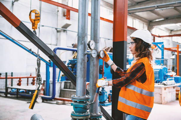 Portrait of young businesswoman working with ball valves in factory Portrait of a serious technician or engineer woman checking pressure device for industry system, opening or closing valve equipment in industrial site factory or utility. air valve stock pictures, royalty-free photos & images