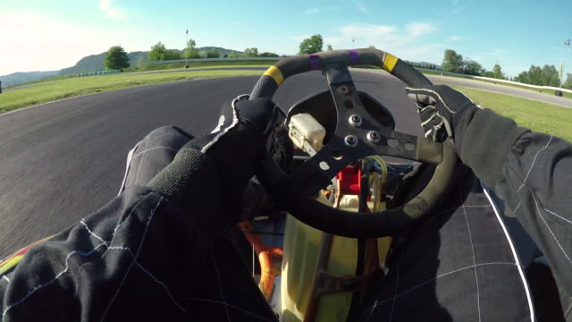 POV: Driving a go-kart in a black suit through sharp bends of a bumpy racetrack.