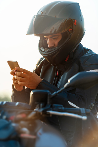 Young man with mobile phone on motorcycle in nature.  The design of the motorcycle has been slightly changed. (with photoshop)