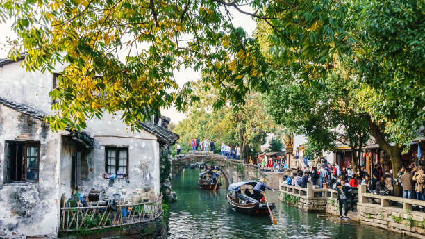 At the Zhouzhuang Water Town, Suzhou, China Suzhou, China - Nov 5, 2016: Boats with tourists cruised by at the historic Zhouzhuang Water Town. Lots of tourists activities along the shoreline and on the ancient bridge. A couple of tour boats pass by with passengers on board. water town zhouzhuang china stock pictures, royalty-free photos & images