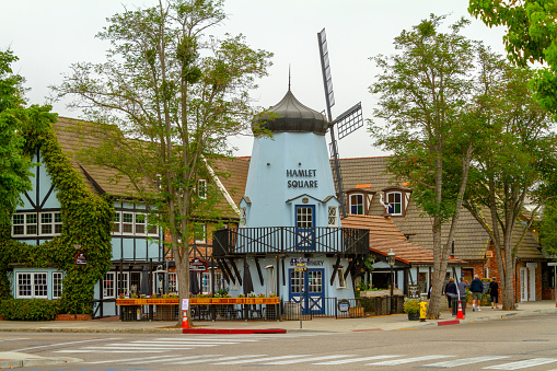 Solvang, CA, USA - August 23, 2018: People walking pass the Hamlet Square Windmill in the Danish-styled village of Solvang in the Santa Ynez Valley of California.