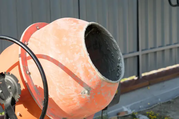 Photo concrete mixer installed on the construction site next to a pile of sand and gravel.