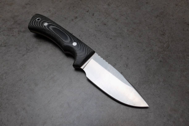istock Hunting knife on a dark gray concrete table 1038465796