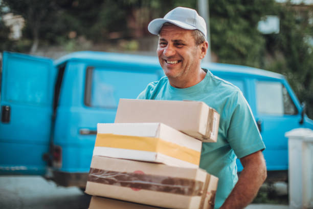 istock Delivery Man Carrying Cardboard Box On Shoulder 1038472826