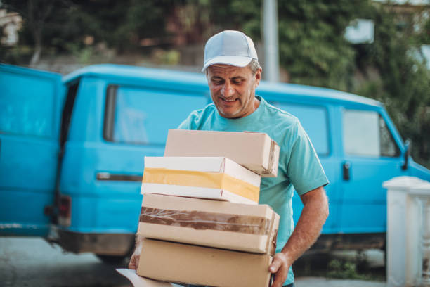 istock Delivery Man Carrying Cardboard Box On Shoulder 1038472920