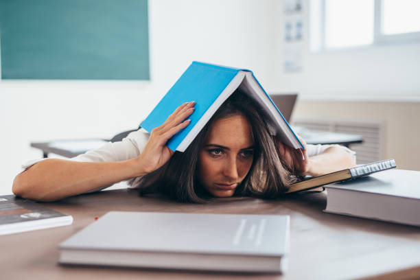 cansado mujer joven durmiendo en el escritorio con libros - open book teaching table fotografías e imágenes de stock