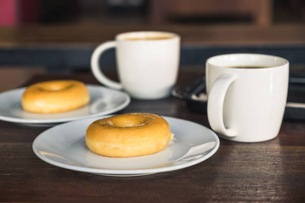 istock Two set of donuts in a white plate with coffee cups on wooden table 1038550008