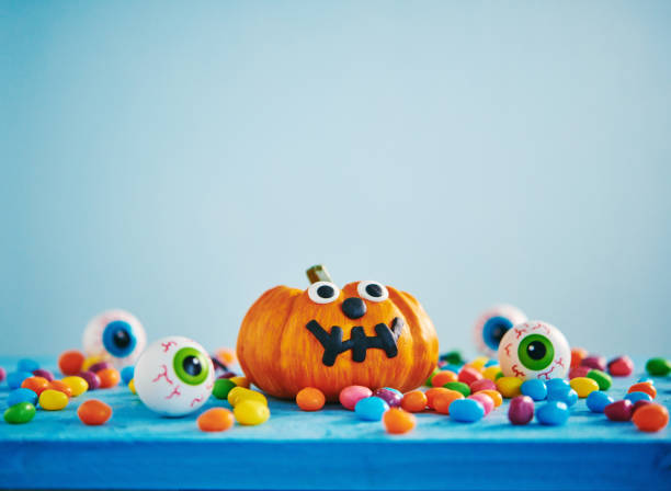 Vibrant Halloween background with pumpkin, candy and eyeballs Vibrant Halloween background with pumpkin, candy and eyeballs miniature pumpkin stock pictures, royalty-free photos & images