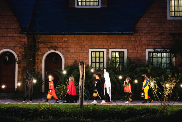 gruppo di bambini con costumi di halloween che camminano per ingannare o trattare - trick or treat foto e immagini stock