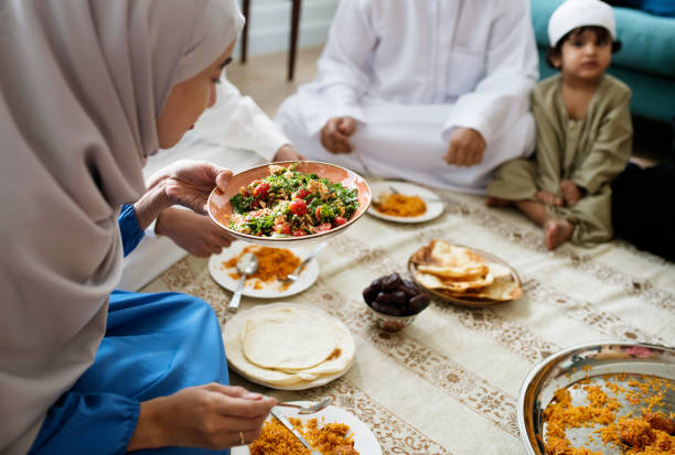 イスラム教徒の家族が夕食を床に - taqiyah ストックフォトと画像