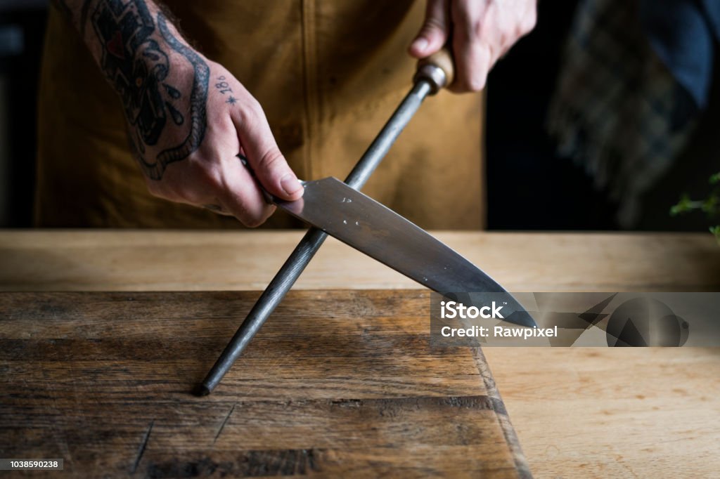 Professional chef sharpening knife in the kitchen Table Knife Stock Photo
