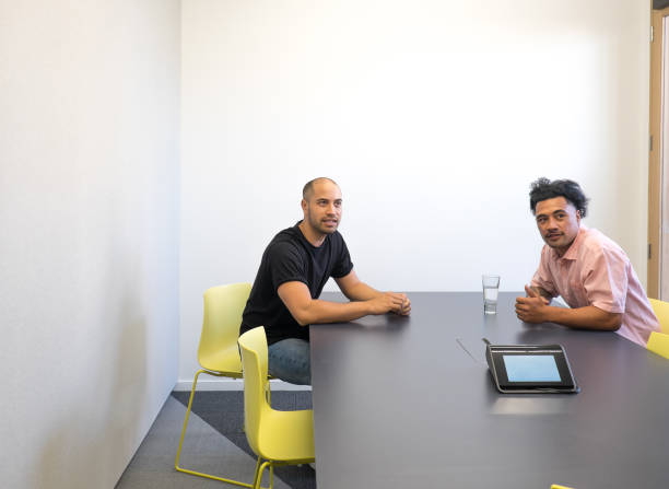 istock Two men in meeting room with table, chairs and phone or video conferencing technology. 1038605828