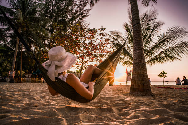 donna che si rilassa sull'amaca sulla spiaggia al tramonto. - hammock beach vacations tropical climate foto e immagini stock