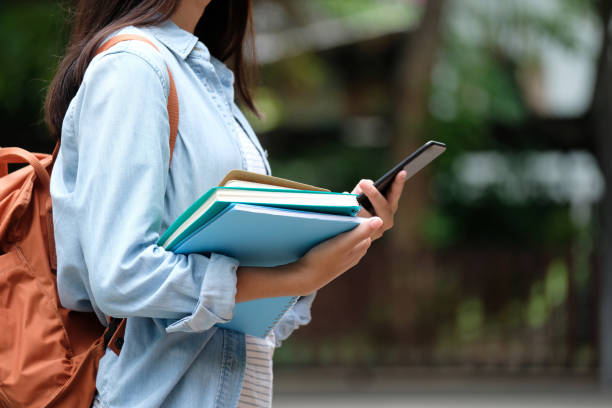 istock Student girl holding books and using smartphone, online education, technology communication 1038645622
