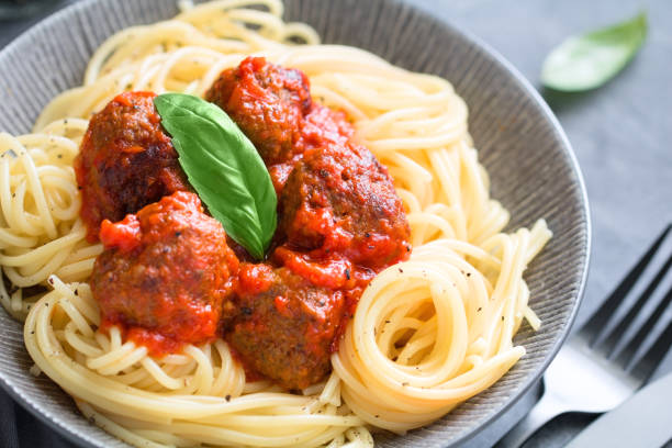 istock Beef meatballs in tomato sauce with Italian spaghetti and fresh basil leaf on a dinner table. Simply homemade recipe, close up. 1038646768