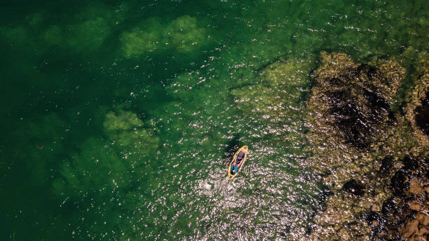 istock Man kayaking along rocky coastline 1038646800