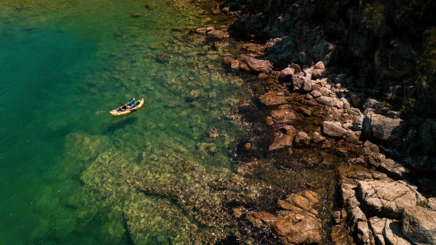 istock Man kayaking along rocky coastline 1038646806