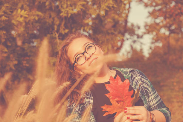 Cute woman holding autumn leafs in nature.