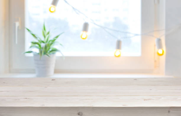 istock Wooden empty board over blurred holiday window with garland lights 1038658338