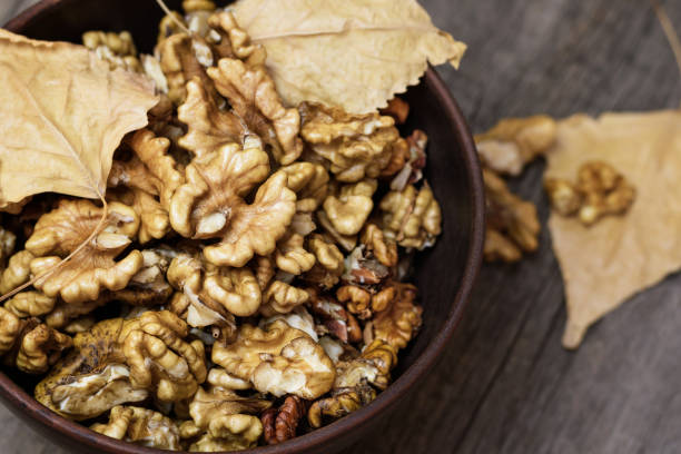 istock Walnuts kernels in a clay bowl on wooden background. 1038662614