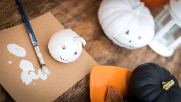 istock DIY decorating little white Halloween pumpkins.  DIY creative Halloween decorations. Hand painted pumpkins and paintbrush on a table. 1038665162