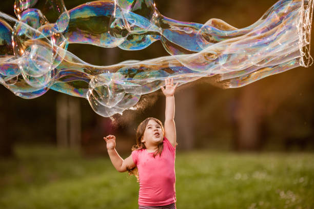 istock Small girl having fun while reaching for rainbow bubbles in nature. 1038665292