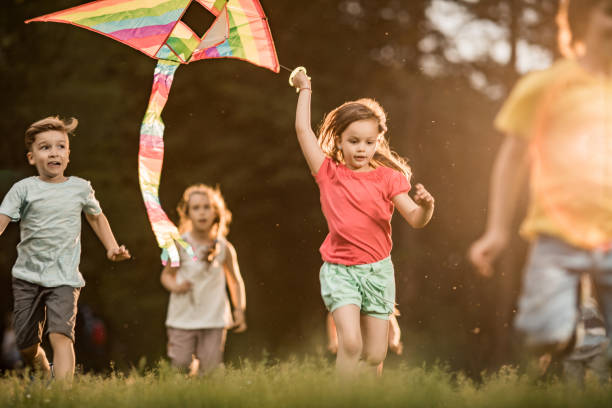 istock Carefree kids having fun while running with a kite at the park. 1038670356