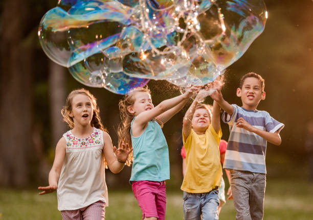 istock Group of children playing with rainbow bubbles in nature. 1038670484