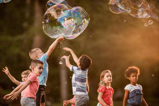 istock Group of kids having fun while playing with bubbles in the park. 1038670960