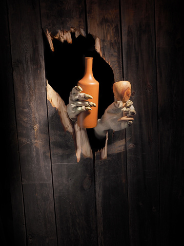 Zombie hand through hole cracked in rustic wood.Halloween theme.