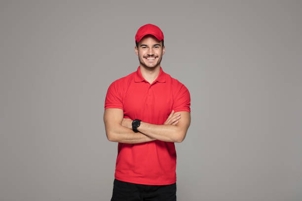 Smiling courier man posing in studio. Delivery Concept - Smiling Caucasian courier man posing on studio background. uniform stock pictures, royalty-free photos & images