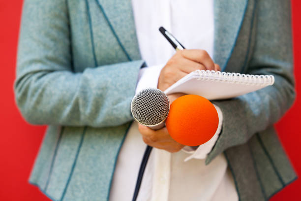 istock Journalist at news conference, writing notes, holding microphone 1038692472